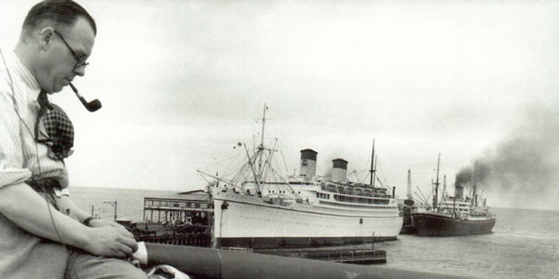 Rev Charles Lavender mends a flag on the roof of the Mission to Seamen building with Station Pier beyond. PMHPS Collection