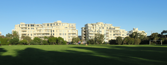 Lagoon Reserve with afternoon shadows cast across the ground with sunlit apartments in the background.