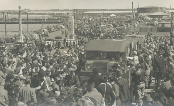 Ambulances carrying returning soldiers make their way through the crowds on Centenary Bridge, 1940s